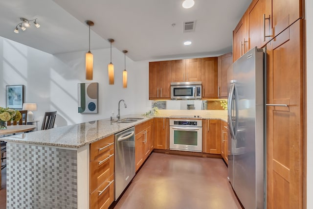 kitchen featuring light stone counters, a peninsula, a sink, stainless steel appliances, and concrete flooring