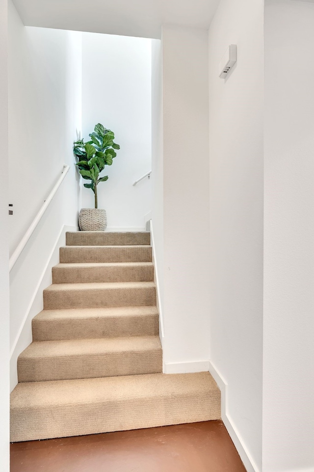 stairway with baseboards and finished concrete floors