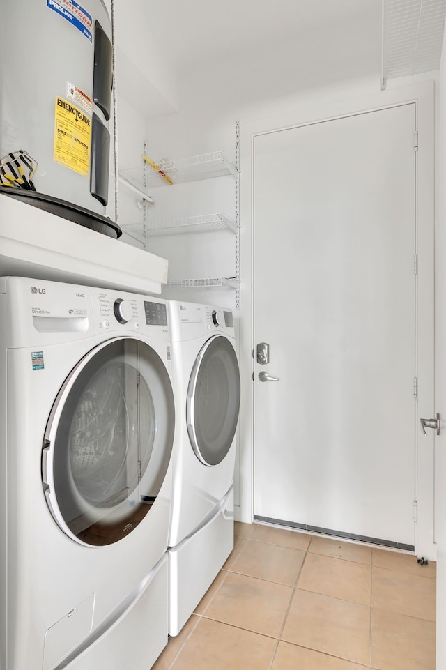 washroom featuring washing machine and dryer, laundry area, and light tile patterned flooring