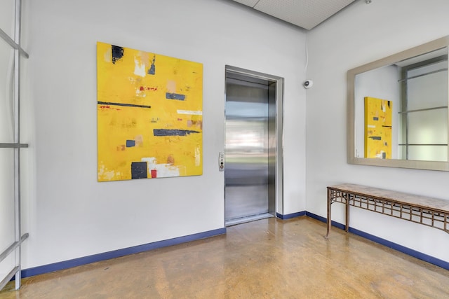interior space featuring concrete flooring, elevator, and baseboards