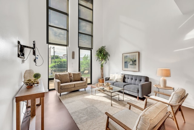 living room featuring concrete floors, a towering ceiling, and baseboards