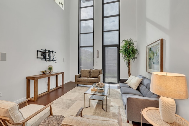 living room with a towering ceiling, baseboards, wood finished floors, and floor to ceiling windows