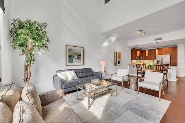 living room with visible vents, baseboards, and finished concrete flooring