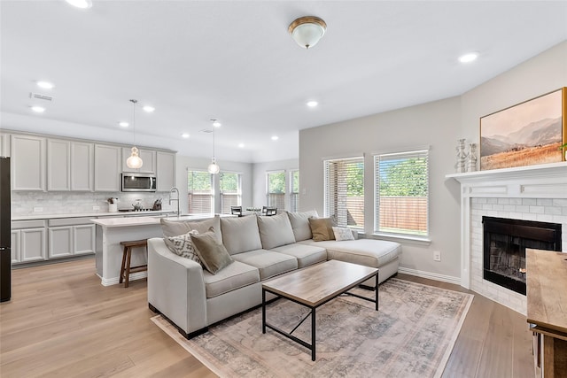 living room featuring a fireplace, light hardwood / wood-style floors, and sink