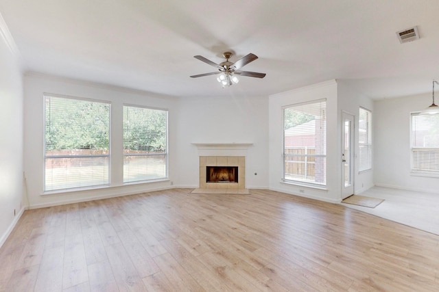 unfurnished living room with ceiling fan, light hardwood / wood-style flooring, a healthy amount of sunlight, and a tile fireplace