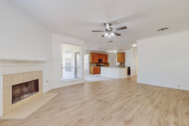 unfurnished living room featuring ceiling fan, light wood-type flooring, a fireplace, and ornamental molding