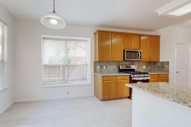 kitchen featuring backsplash, stainless steel appliances, plenty of natural light, and hanging light fixtures