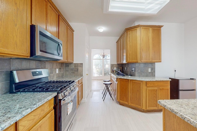 kitchen with appliances with stainless steel finishes, tasteful backsplash, and light stone counters