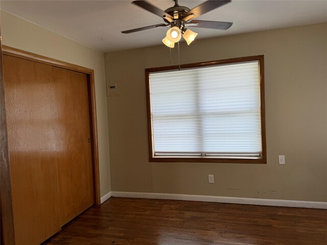 unfurnished bedroom featuring a closet, ceiling fan, and dark hardwood / wood-style flooring