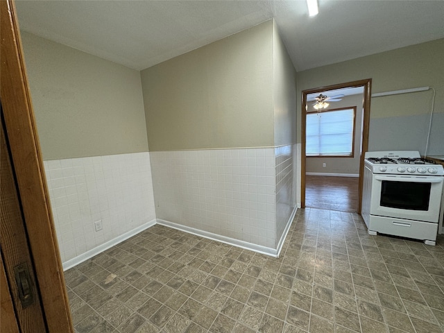 kitchen featuring tile walls, ceiling fan, and white gas range oven