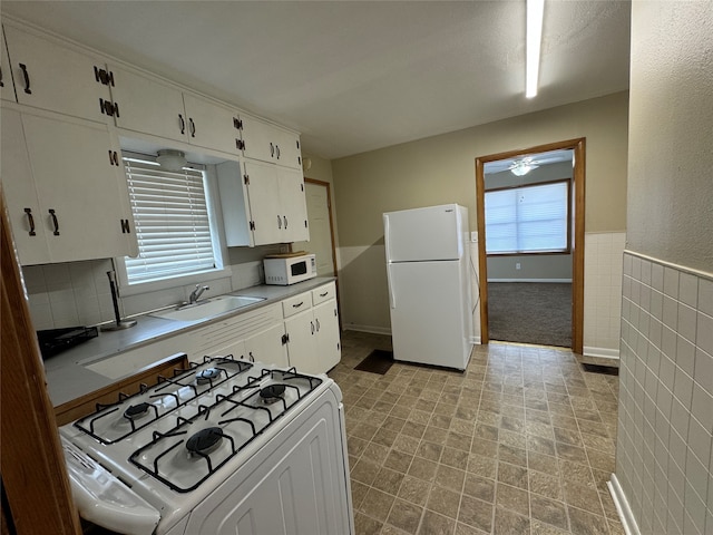 kitchen featuring tile walls, white appliances, sink, and white cabinets