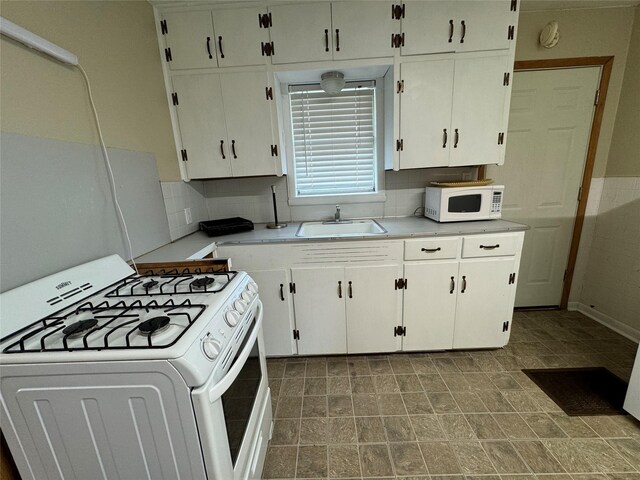 kitchen with white appliances, tasteful backsplash, white cabinetry, and sink