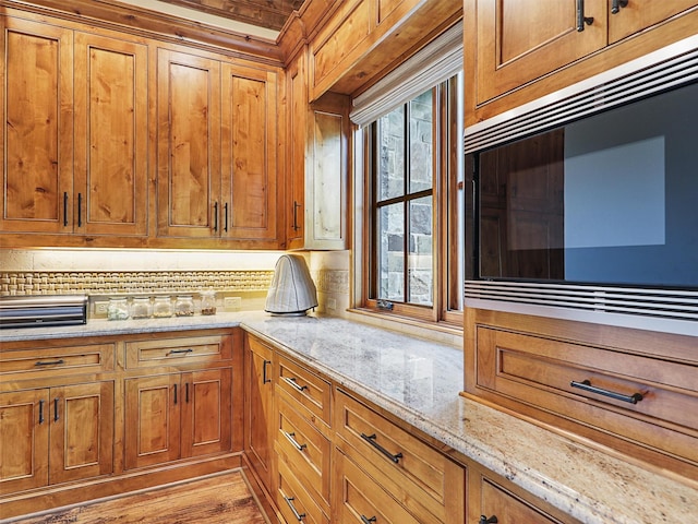 kitchen with built in microwave, light stone counters, and light wood-type flooring