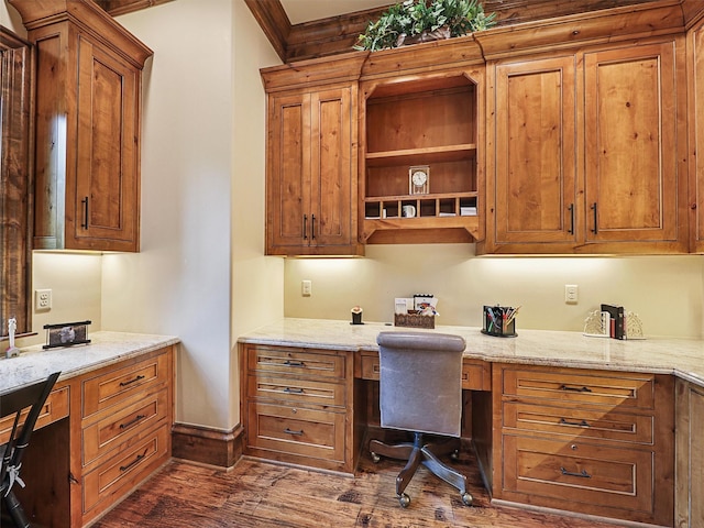 office space with dark wood-type flooring, built in desk, and ornamental molding