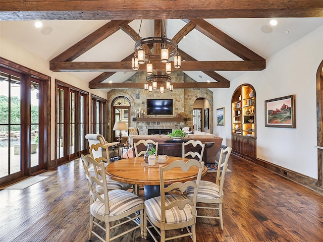 dining space with a notable chandelier, dark hardwood / wood-style floors, beam ceiling, and a fireplace