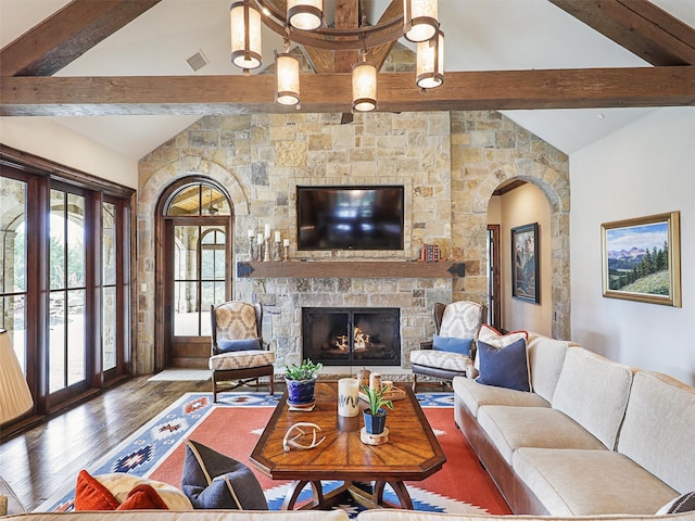 living room with hardwood / wood-style flooring, lofted ceiling with beams, and a stone fireplace