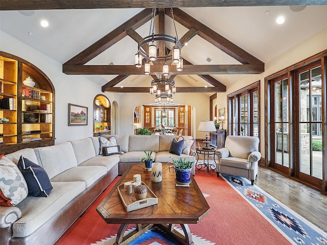 living room with built in shelves, lofted ceiling with beams, and a notable chandelier