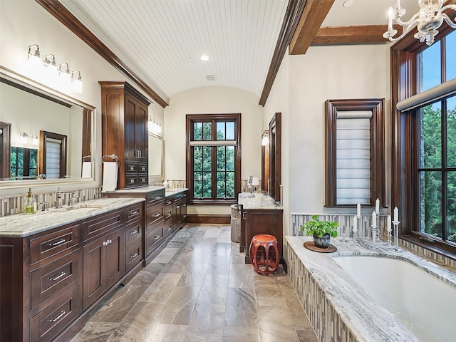 bathroom featuring a chandelier, lofted ceiling, vanity, and a tub