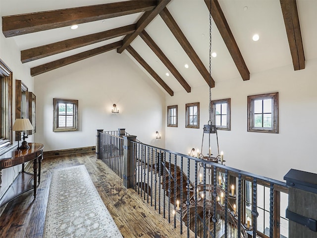 corridor featuring beamed ceiling, high vaulted ceiling, plenty of natural light, and a notable chandelier