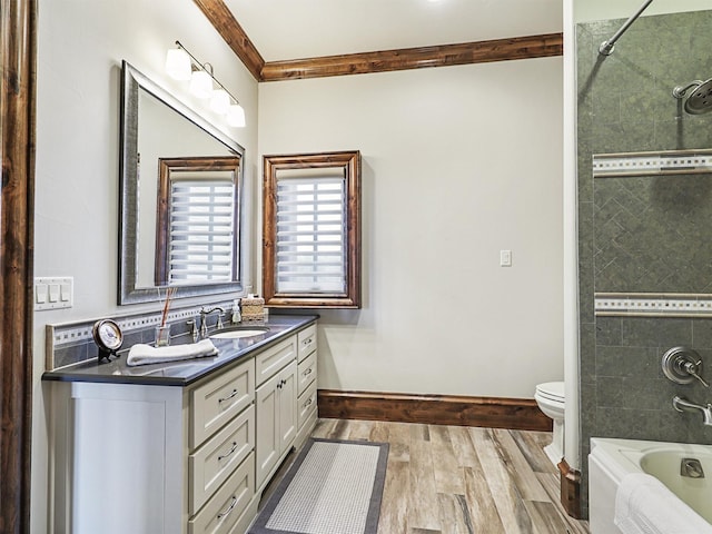 full bathroom with ornamental molding, vanity, tiled shower / bath combo, hardwood / wood-style flooring, and toilet