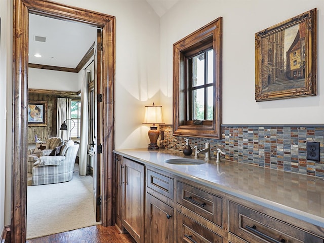 bar featuring hardwood / wood-style floors, backsplash, ornamental molding, and sink