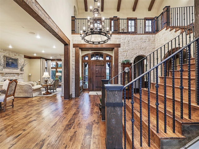 entryway featuring a high ceiling, a healthy amount of sunlight, beam ceiling, a notable chandelier, and hardwood / wood-style floors