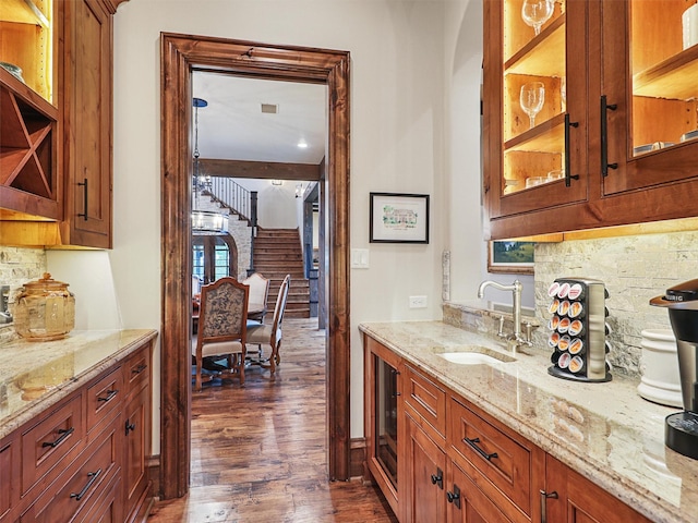 bar featuring tasteful backsplash, dark hardwood / wood-style flooring, light stone counters, and sink