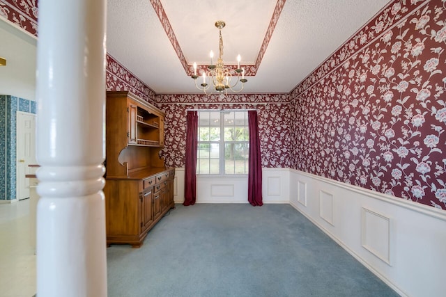 spare room with carpet flooring, a chandelier, decorative columns, and a textured ceiling