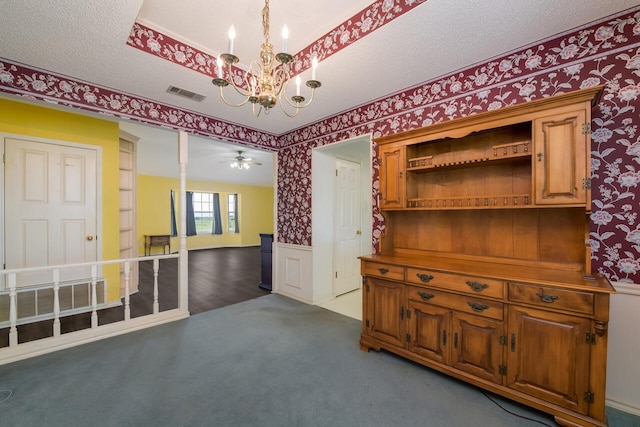 empty room featuring a textured ceiling, carpet, and ceiling fan with notable chandelier