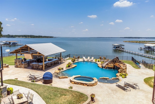 view of swimming pool with an in ground hot tub, a water view, and exterior bar