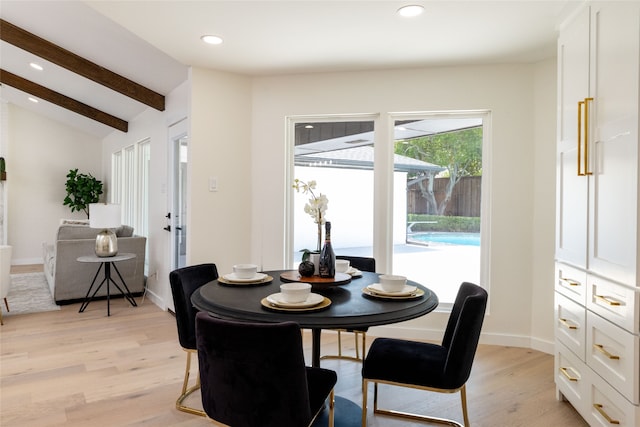 dining room featuring vaulted ceiling with beams and light hardwood / wood-style flooring