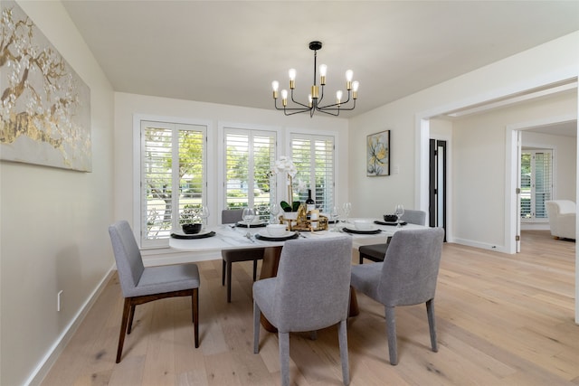 dining room with a healthy amount of sunlight, light wood-type flooring, and a notable chandelier