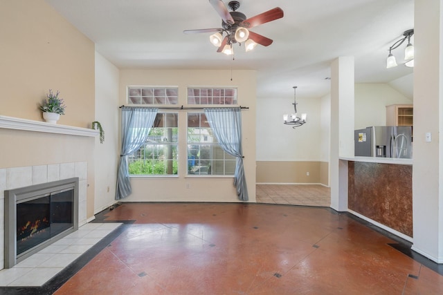 unfurnished living room with tile patterned flooring, ceiling fan with notable chandelier, lofted ceiling, and a tile fireplace