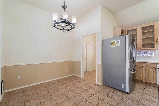 kitchen featuring stainless steel fridge, backsplash, a notable chandelier, hanging light fixtures, and lofted ceiling