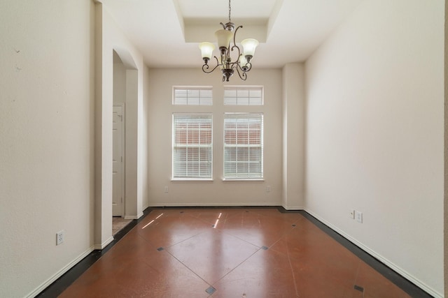 unfurnished dining area featuring a raised ceiling, dark tile patterned floors, and an inviting chandelier