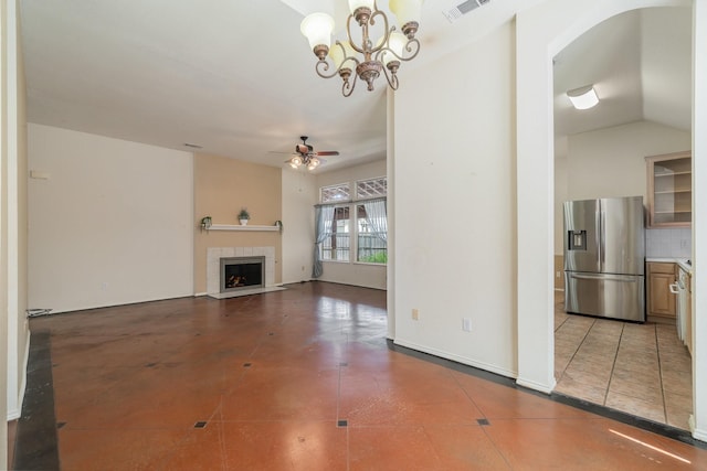 unfurnished living room featuring ceiling fan with notable chandelier, tile patterned floors, vaulted ceiling, and a tiled fireplace