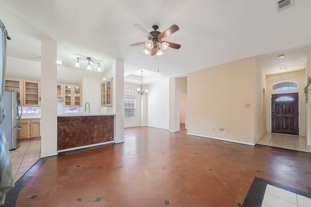 unfurnished living room with tile patterned flooring, ceiling fan with notable chandelier, and sink