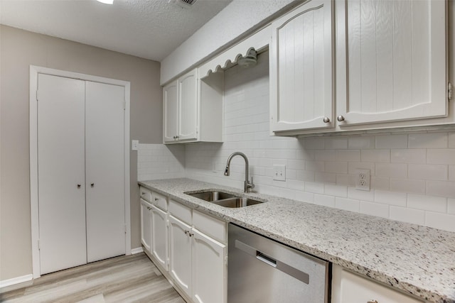 kitchen with white cabinets, tasteful backsplash, sink, dishwasher, and light hardwood / wood-style floors