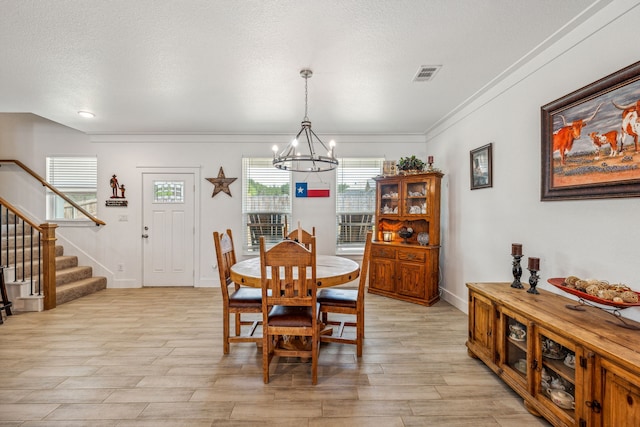 dining space with crown molding, a textured ceiling, and an inviting chandelier