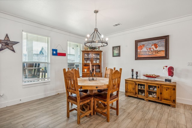 dining area featuring light hardwood / wood-style floors, crown molding, and a chandelier