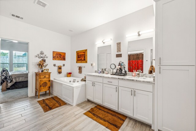 bathroom featuring dual vanity and a bathtub