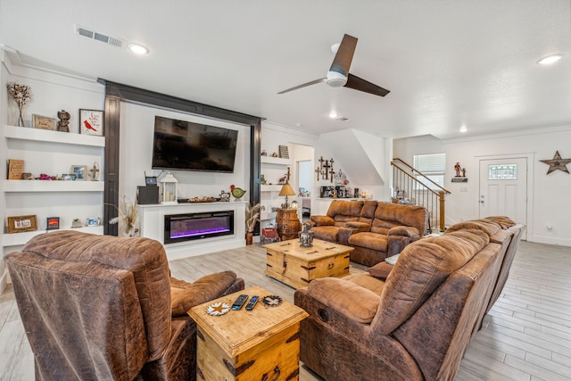 living room featuring ceiling fan, built in features, ornamental molding, and light hardwood / wood-style flooring