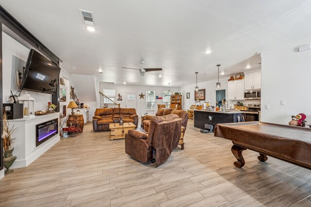 interior space with sink, pool table, ceiling fan, and light wood-type flooring