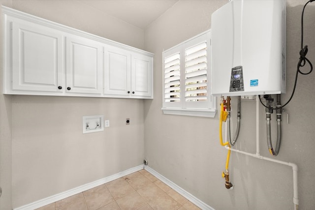 washroom with electric dryer hookup, water heater, washer hookup, cabinets, and light tile patterned floors