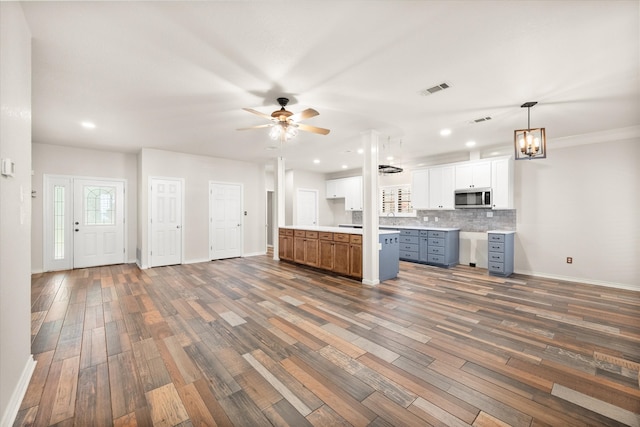 unfurnished living room featuring ceiling fan with notable chandelier and hardwood / wood-style floors