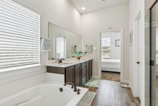 bathroom with wood-type flooring, vanity, and plus walk in shower