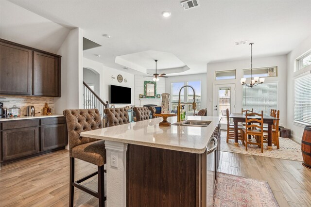 kitchen featuring a center island with sink, sink, a kitchen breakfast bar, and light hardwood / wood-style floors