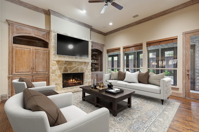 living room with hardwood / wood-style flooring, ornamental molding, ceiling fan, and a fireplace