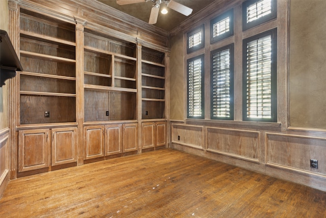 empty room featuring crown molding, wood-type flooring, built in features, and ceiling fan