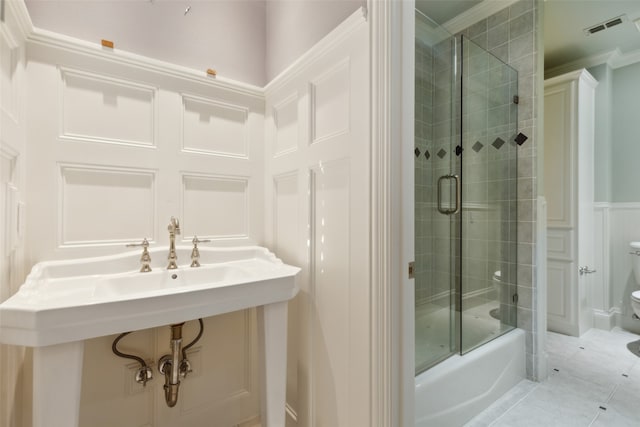 bathroom with tile patterned flooring, bath / shower combo with glass door, and toilet